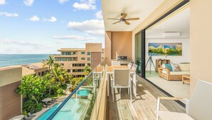 A balcony with a pool, outdoor seating, and a view of the ocean.