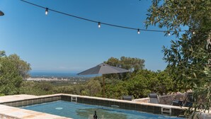A swimming pool with stone tiles, a bottle, and glasses on the edge, surrounded by greenery and a view of the sea. - Palazzina Tommaso Sea View & Wellness "Adults Only" between Ostuni and Fasano (Fasano)