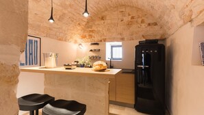 A kitchen with a stone ceiling, a black refrigerator, a wooden countertop, and two black stools. - Palazzina Tommaso Sea View & Wellness "Adults Only" between Ostuni and Fasano (Fasano)