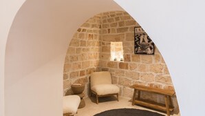 A stone-walled room with a high arched ceiling, a chair, a small table, and a wall-mounted artwork. - Palazzina Tommaso Sea View & Wellness "Adults Only" between Ostuni and Fasano (Fasano)
