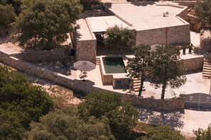 Vista aérea de uma propriedade com piscina, muros de pedra e árvores.