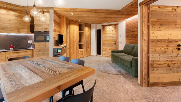 A modern interior with a wooden dining table, chairs, a sofa, and a TV. - Apartment 'Rododendro' with Mountain View, Private Garden and Wi-Fi (Isolaccia)