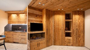 A modern kitchen with wooden cabinetry, a built-in TV, and a fish tank. - Apartment 'Rododendro' with Mountain View, Private Garden and Wi-Fi (Isolaccia)