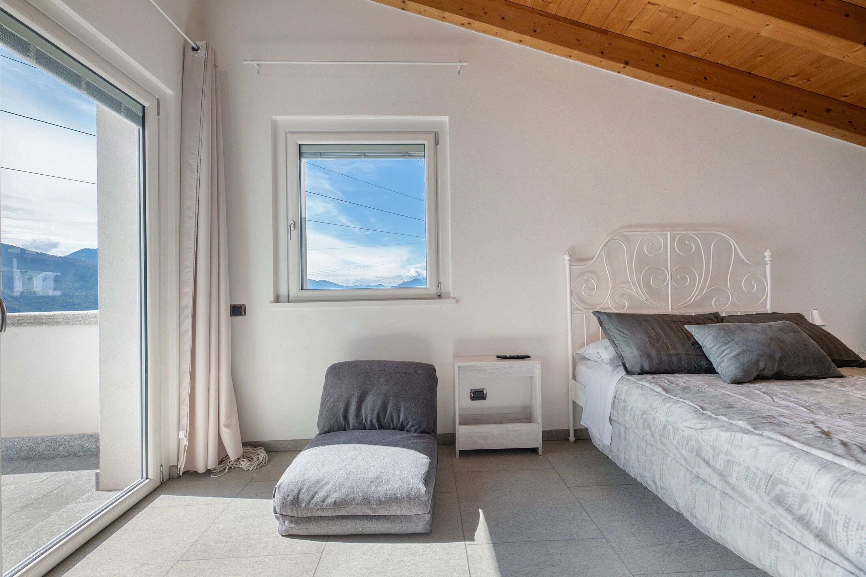 Une chambre à coucher avec un lit, une table de chevet, une fenêtre et une vue sur l’extérieur.