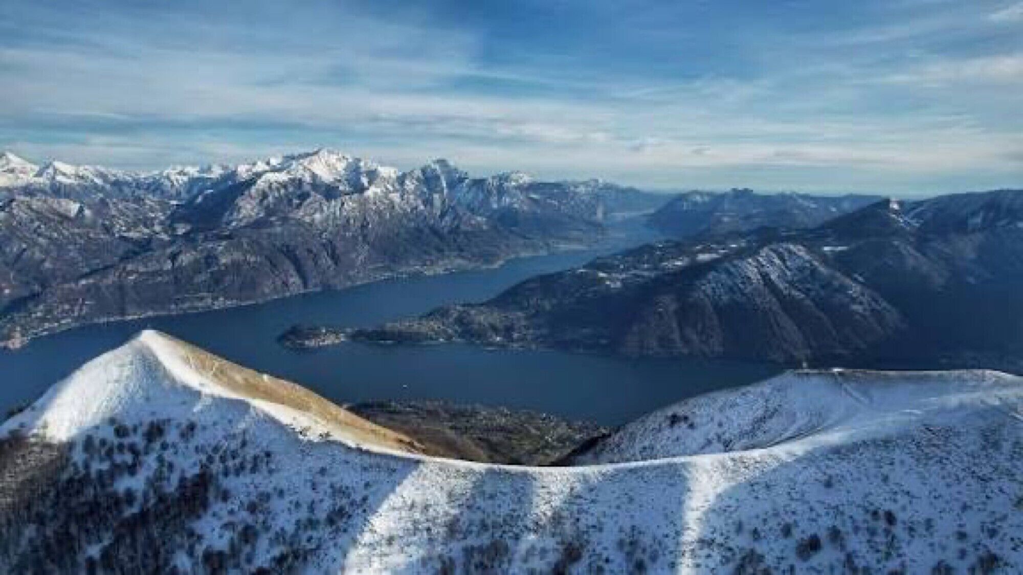 Paesaggio montuoso con cime innevate e un lago.