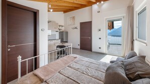 A bedroom with a bed, a desk, and a view of the outside. - Holiday Home 'Il Nido Del Colibrì' with Lake View, Private Terrace & Wi-Fi (Stazzona)