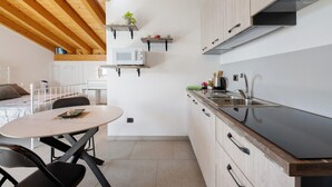 A modern kitchen with wooden beams, a white countertop, and built-in cabinets. - Holiday Home 'Il Nido Del Colibrì' with Lake View, Private Terrace & Wi-Fi (Stazzona)