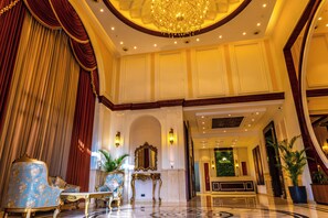 A grand lobby with a chandelier, ornate furniture, and a reception desk. - Maribella Hotel & Resort  (Amritsar)