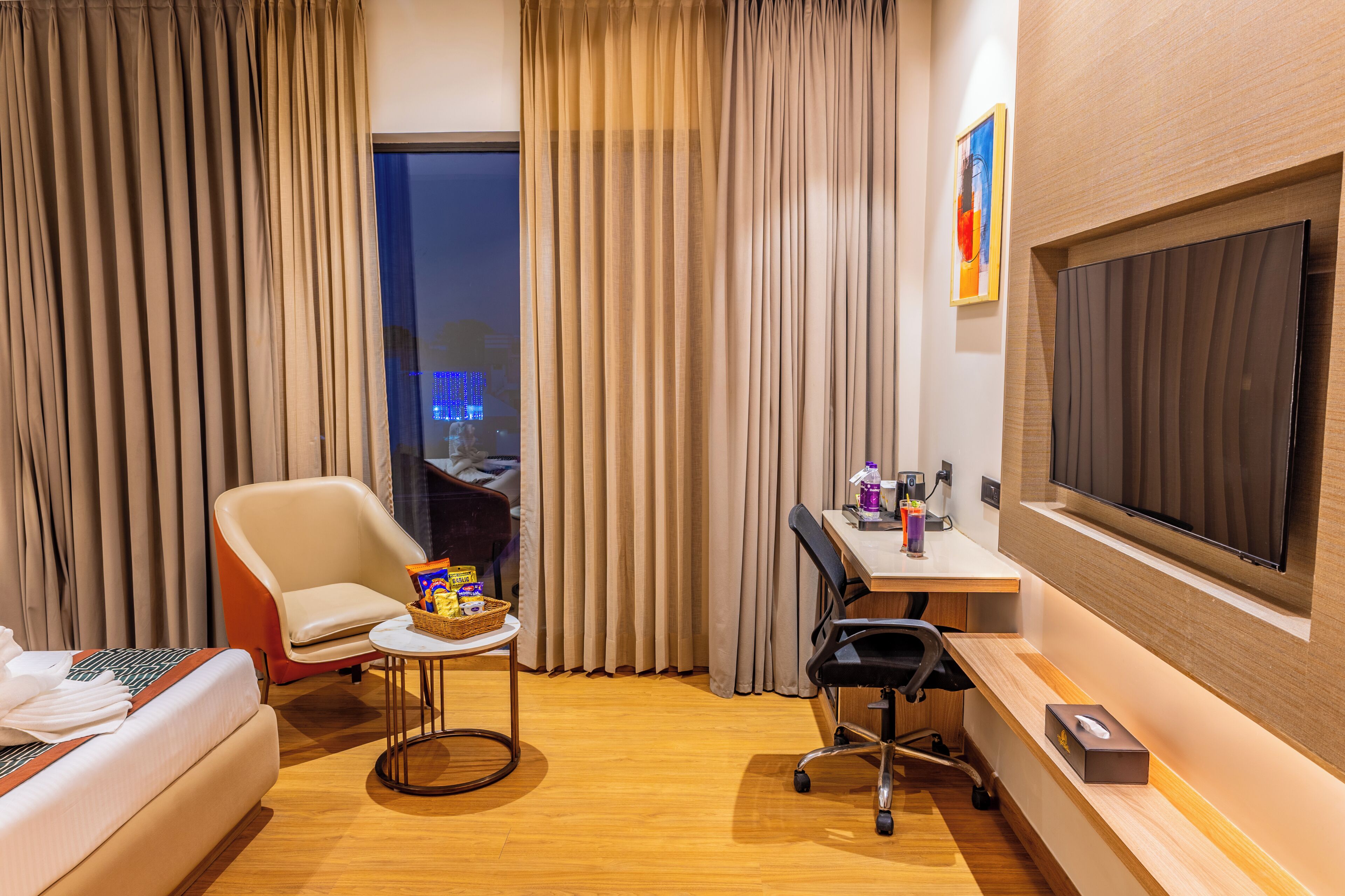 Une chambre d’hôtel équipée d’un lit, d’un bureau, d’une chaise, d’une télévision et offrant une vue sur le paysage urbain.