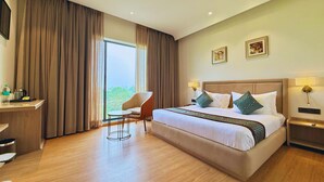 A hotel room with a large bed, a desk, a chair, and a view of the outdoors. - Maribella Hotel & Resort  (Amritsar)