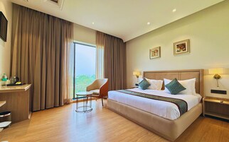 Habitación de hotel con una cama grande, un escritorio, una silla y vistas al exterior.