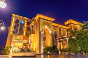 A large building with arched windows and a fountain in the foreground.