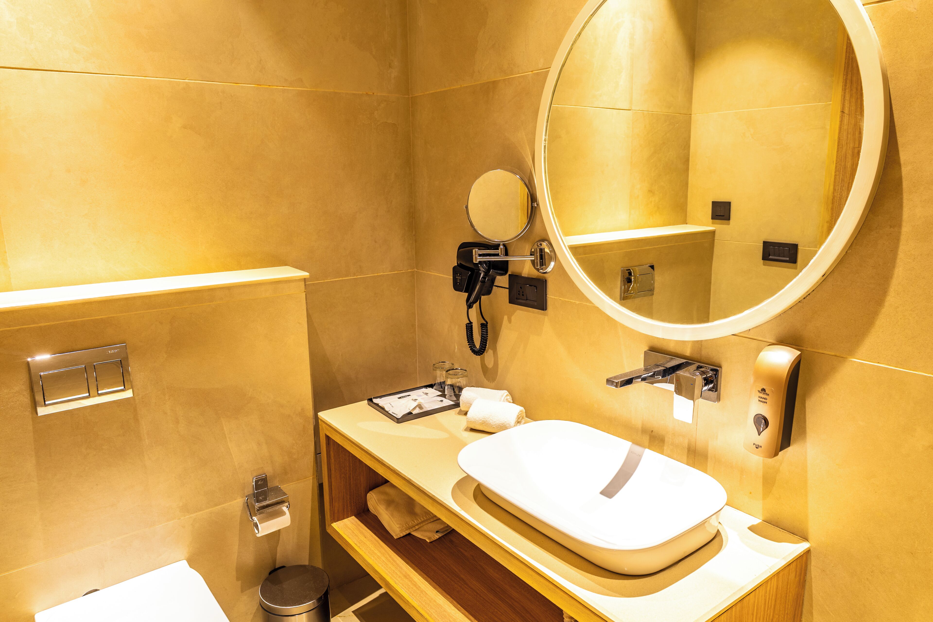 Een badkamer met een wastafel, spiegel, zeepdispenser en toilet.