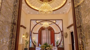 A grand lobby with a chandelier, a round table with flowers, and a red curtain backdrop. - Maribella Hotel & Resort  (Amritsar)