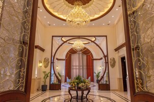 A grand lobby with a chandelier, a round table with flowers, and a red curtain backdrop.