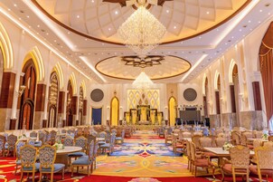 A grand hall with a central altar, ornate chandeliers, and rows of tables and chairs.