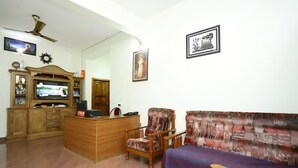 A living room with a wooden cabinet, a television, a sofa, and a chair. - Periyar Canopy Thekkady (Kumily)