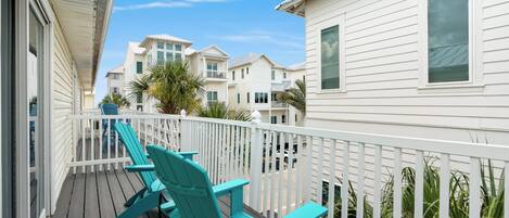 A balcony with teal Adirondack chairs and a white railing.