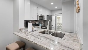 A modern kitchen with white cabinets, a stainless steel sink, and a marble countertop. - Inlet Beach + Gulf View, Pet Friendly & Bikes (Inlet Beach)