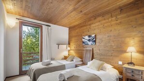 A room with two beds, wooden walls, a window with a view of greenery, and a painting on the wall. - 200m ski slopes-Chalet Manora -Courchevel La Tania (Courchevel)