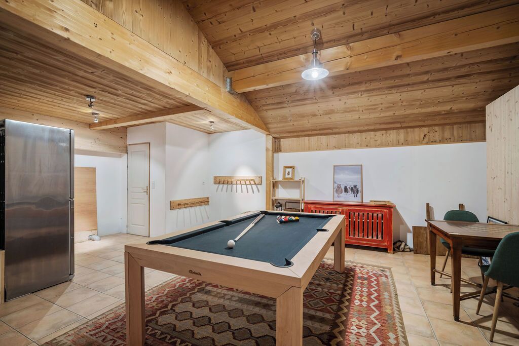 Ein gemütliches Zimmer mit Billardtisch, Kühlschrank und Holzboden.