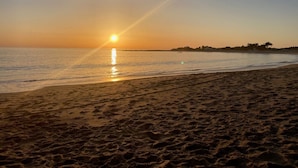 Une plage au coucher du soleil, avec une eau calme et un ciel dégagé.