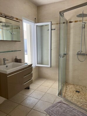 Een moderne badkamer met een douchecabine van glas, een wastafel met spiegel en een wasbak.
