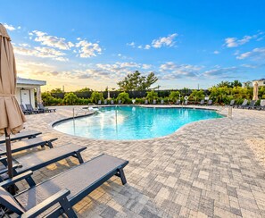 A swimming pool with lounge chairs and umbrellas, surrounded by a paved deck. - Eco-friendly Home with Pool and Elevator! Near the Anna Maria Sound! The Renata (Cortez)
