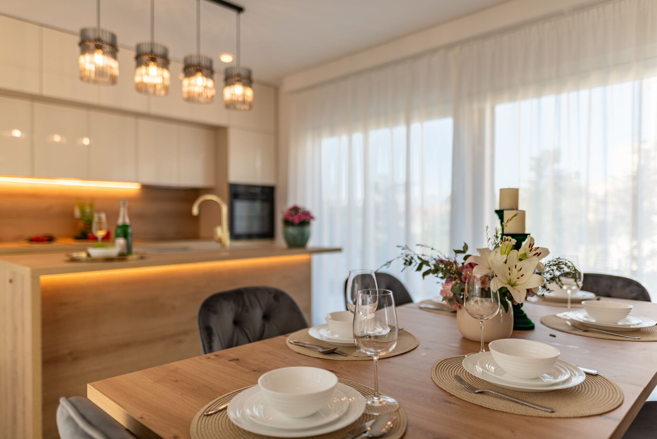 Un comedor moderno con una mesa de madera dispuesta para cuatro personas, con platos, tazones y cubiertos.