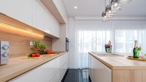 Eine moderne Küche mit weißen Schränken, einer Holz Arbeitsplatte, einem schwarzen Fliesenboden und einer Pendelleuchte.