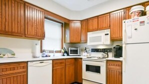 A compact kitchen with wooden cabinets, a microwave, a stove, and a refrigerator.