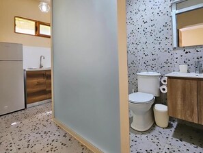 A compact kitchen with a refrigerator, wooden cabinets, and a window above the sink. - Lemon House Borsh (Lukovë)