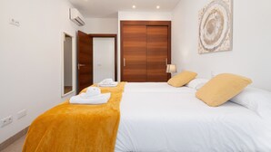Habitación de hotel con cama, armario de madera, una obra de arte en la pared y baño visible a través de una puerta abierta.