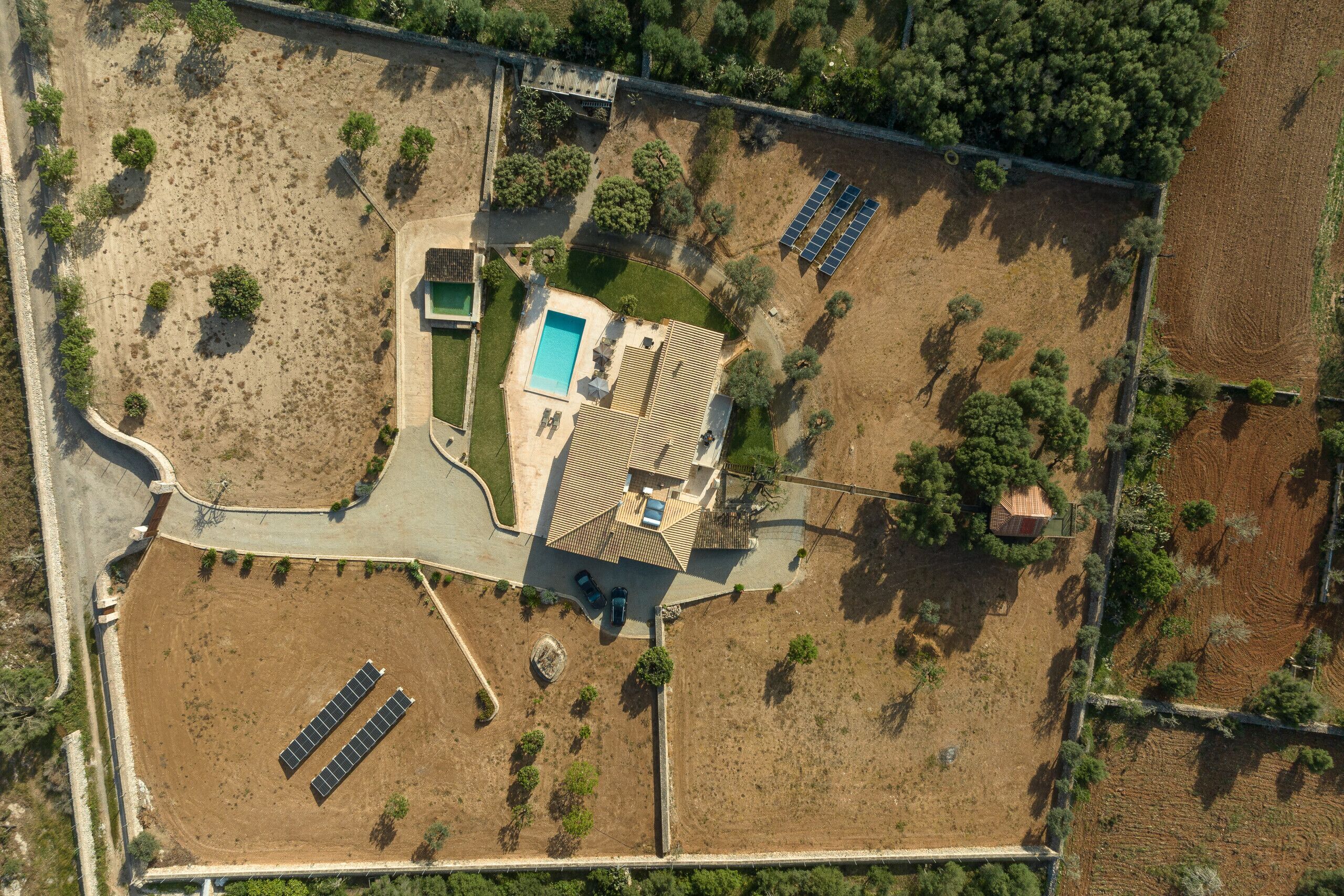 Vue aérienne d’une propriété dotée d’une piscine, de panneaux solaires et d’une petite maison.