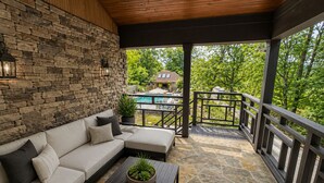 A covered outdoor seating area with a stone floor, a sofa, and a coffee table.