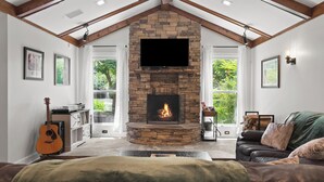 A cozy living room with a stone fireplace, a guitar, and a leather couch.