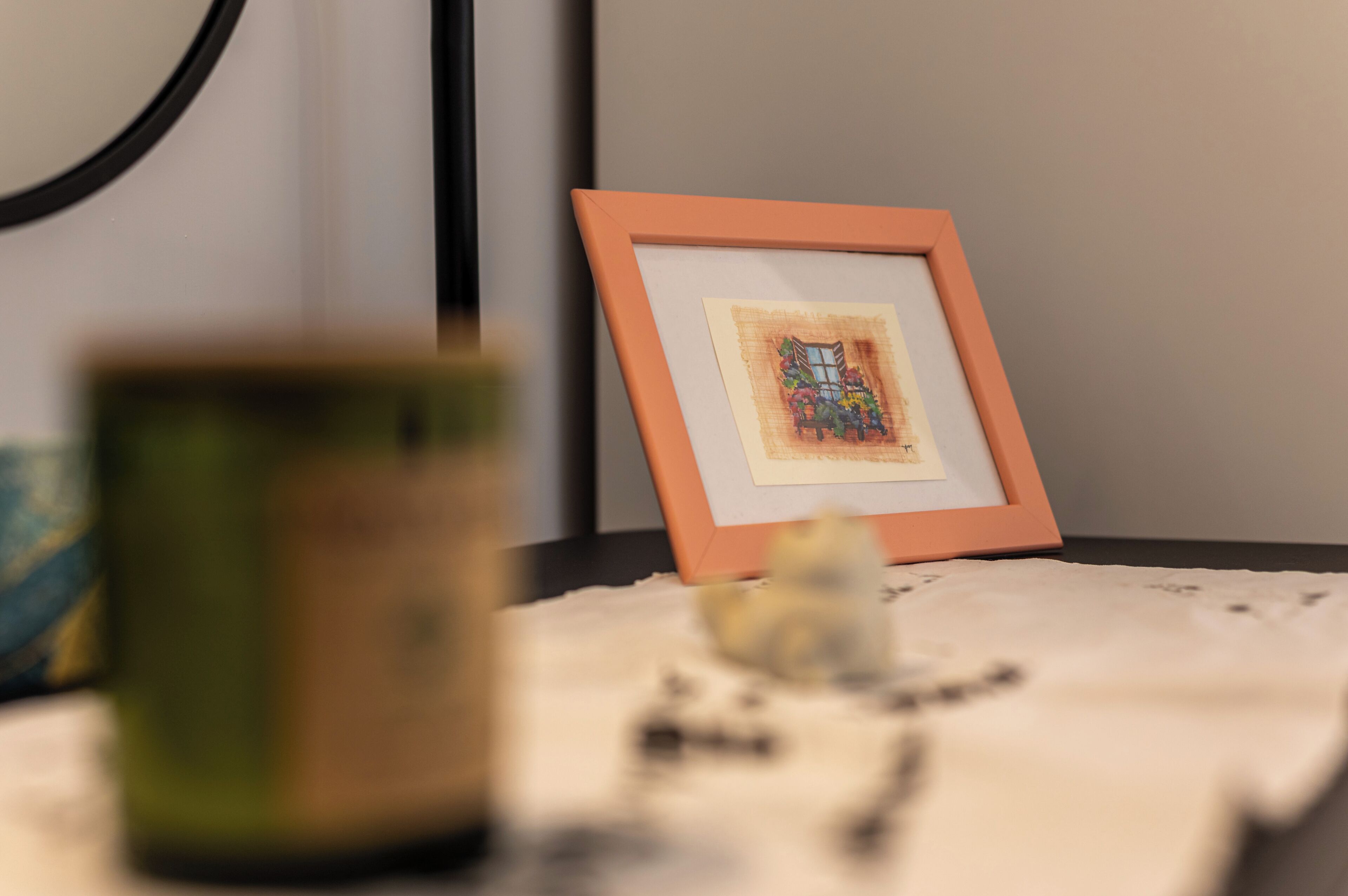 A framed artwork on a table with a candle and scattered items.