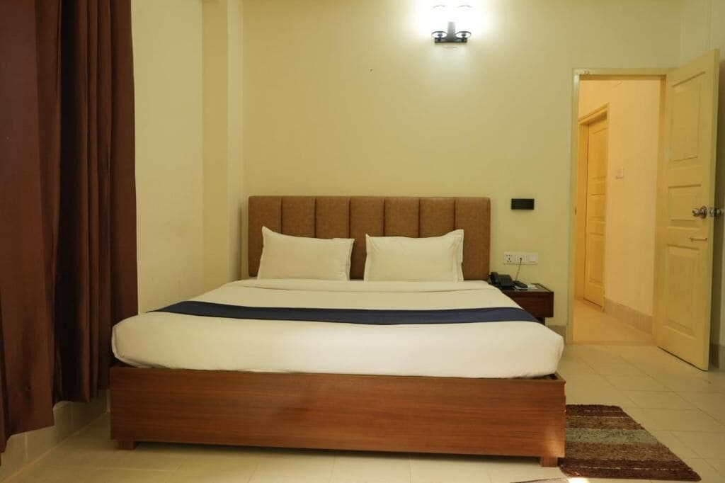 Ein Schlafzimmer mit einem hölzernen Bett, weißer Bettwäsche, einem Nachttisch und einer Wandleuchte.