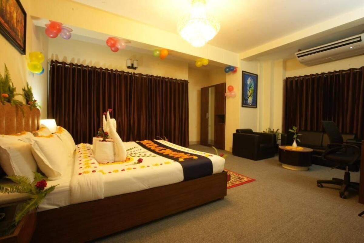 A hotel room with a bed, a desk, a chair, and a potted plant.