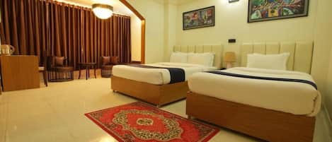 Habitación de hotel con dos camas, una alfombra roja, un escritorio y una silla.
