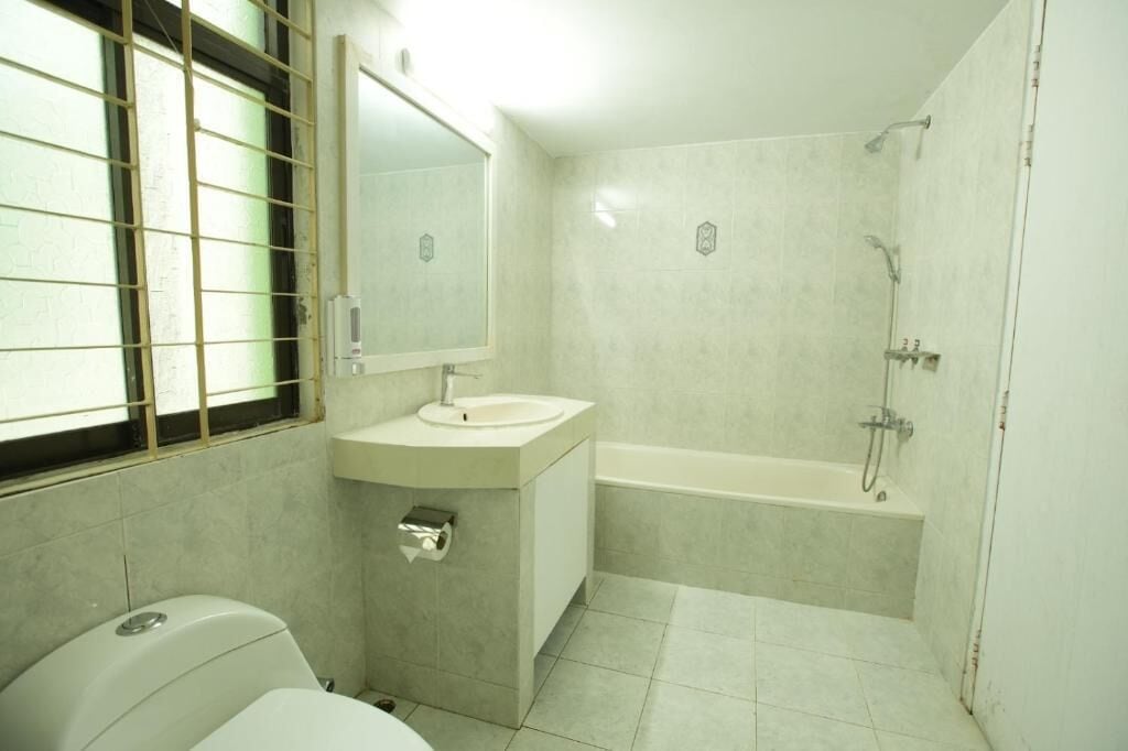 A bathroom with a toilet, sink, mirror, and bathtub.