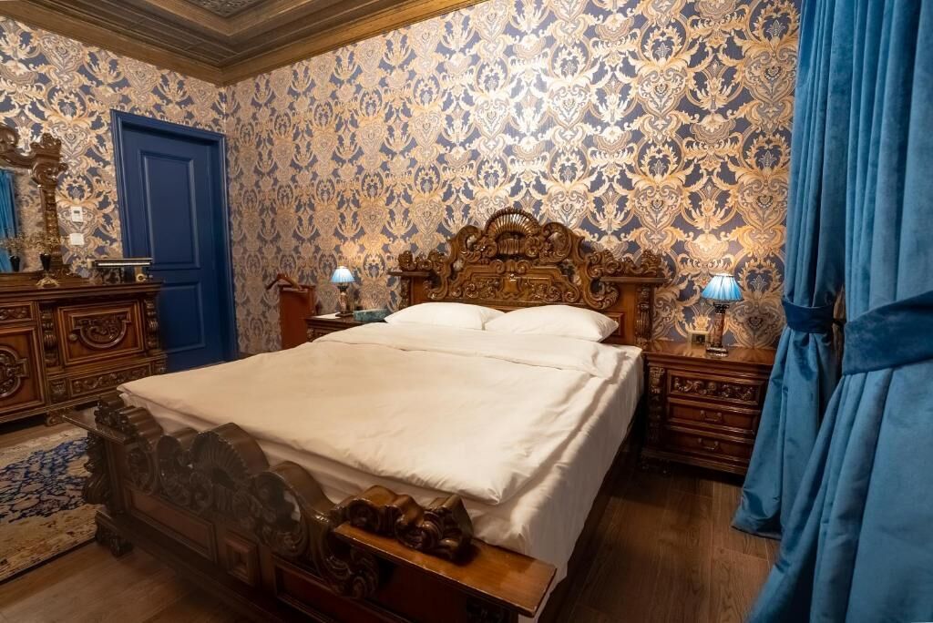 A traditional bedroom with a large bed, ornate wooden headboard, and matching nightstands.