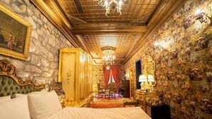 Une chambre à coucher luxueuse, dotée d’un grand lit, de meubles richement décorés et d’un lustre.