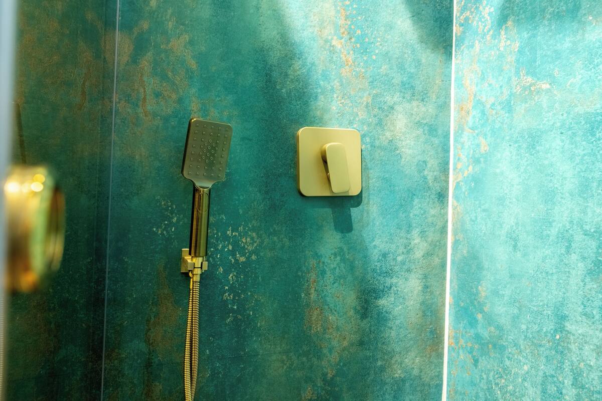 Une salle de bain équipée d’une douche, d’un pommeau de douche amovible et d’un interrupteur.