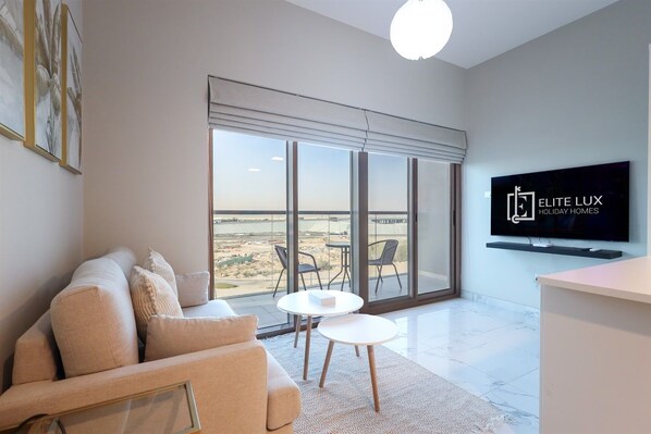 A modern living room with a large window, a sofa, a coffee table, and a flat-screen TV.