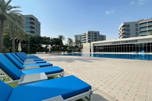A poolside area with lounge chairs, a pool, and a building labeled 'MAG 5 CLUBHOUSE'. - Cozy 2BR Getaway Minutes from Expo City, Dubai (Dubai)