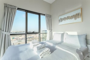 A hotel room with a large bed, a view of the city through the window, and a framed artwork on the wall. - Cozy 2BR Getaway Minutes from Expo City, Dubai (Dubai)