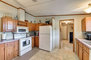 A kitchen with wooden cabinets, a microwave, stove, refrigerator, and a sink.