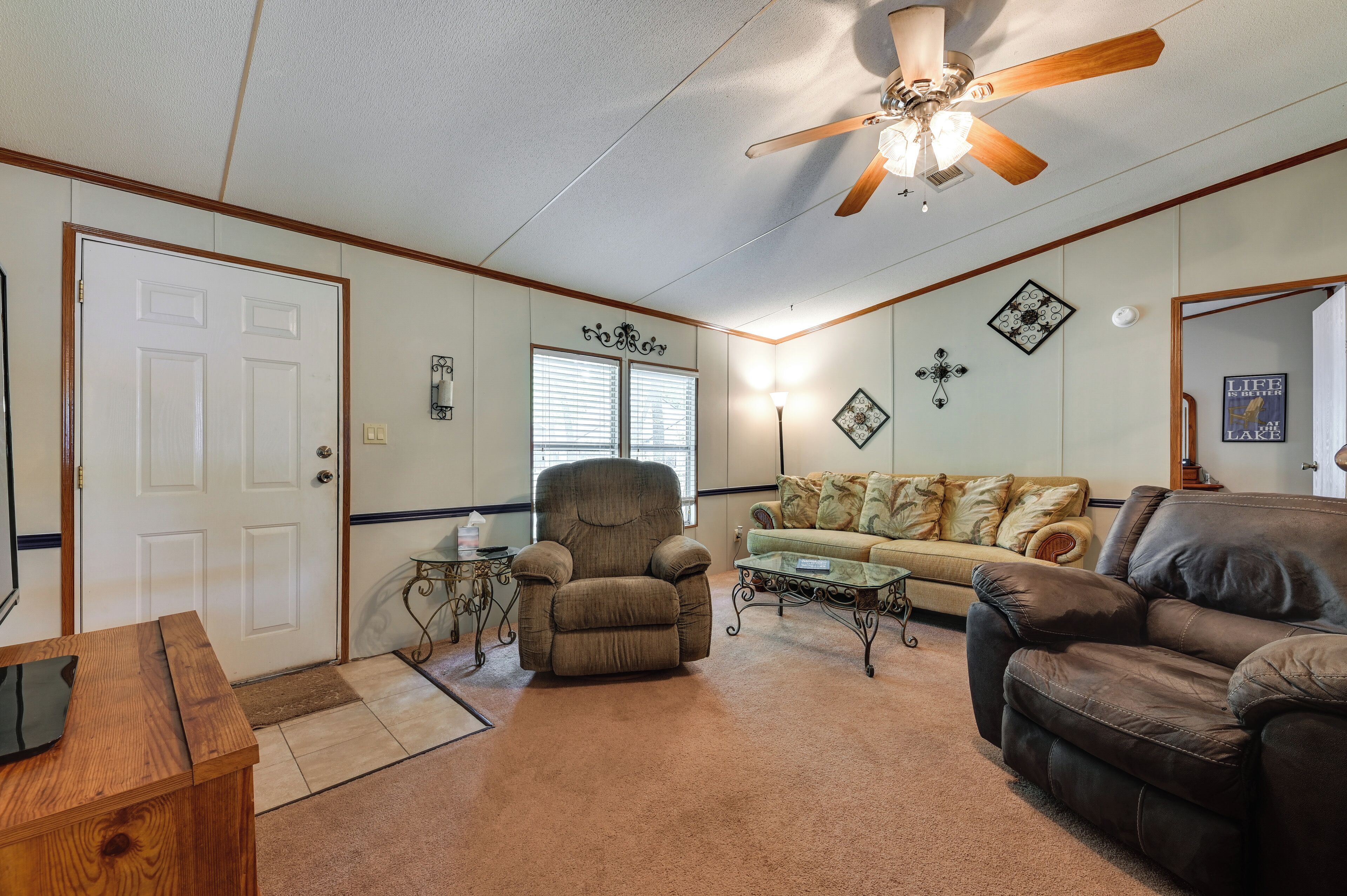 A living room with a ceiling fan, a brown armchair, a beige sofa, and a brown leather couch.