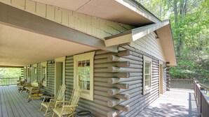 Une cabane en rondins avec une véranda, des fauteuils à bascule et une grande fenêtre.